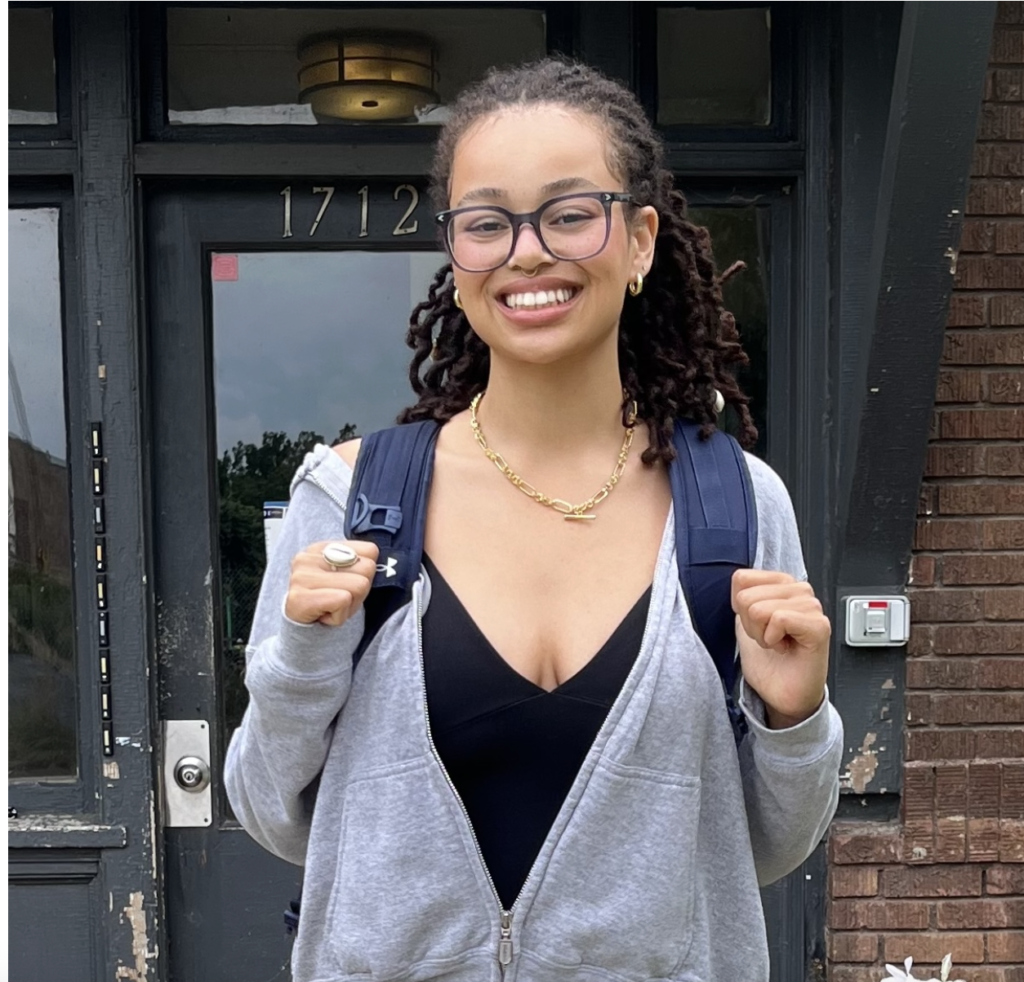 Rabi Michael-Crushshon poses for a photo while carrying a backpack. 